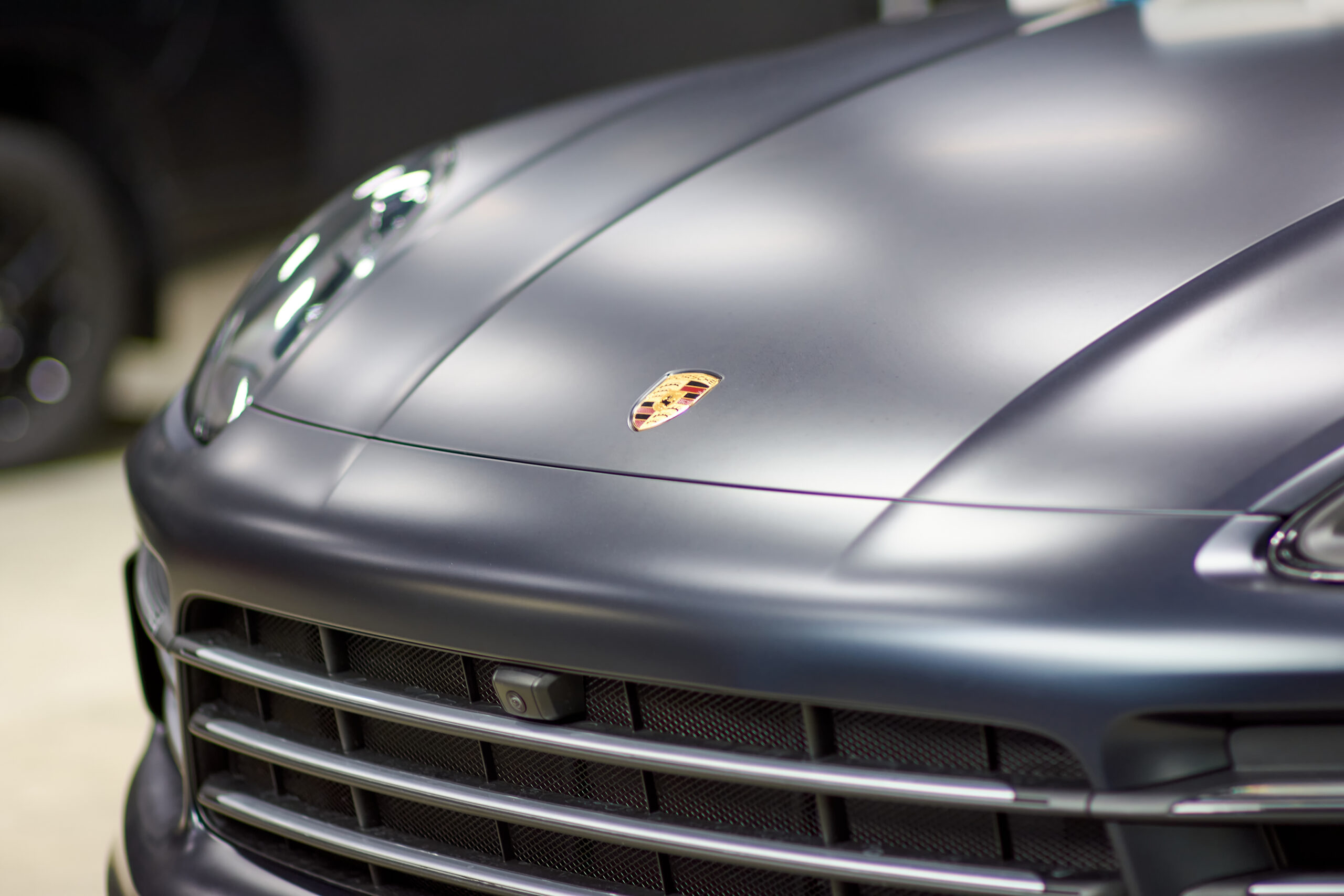 Installation of a protective paint and varnish matte film on a black Porsche Cayenne car. PPF polyurethane film protects car paint from stones, blurred focus. Chelyabinsk, Russia, April 03, 2021